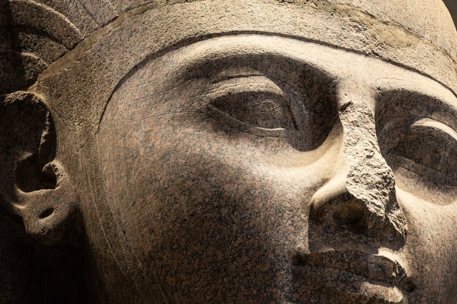 Detailed close-up of ancient Egyptian stone statue in warm lighting.