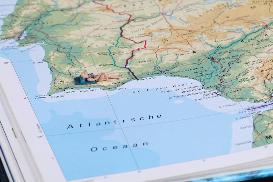 A creative scene with a miniature figure sunbathing on a detailed geographic map of Spain's coastline.