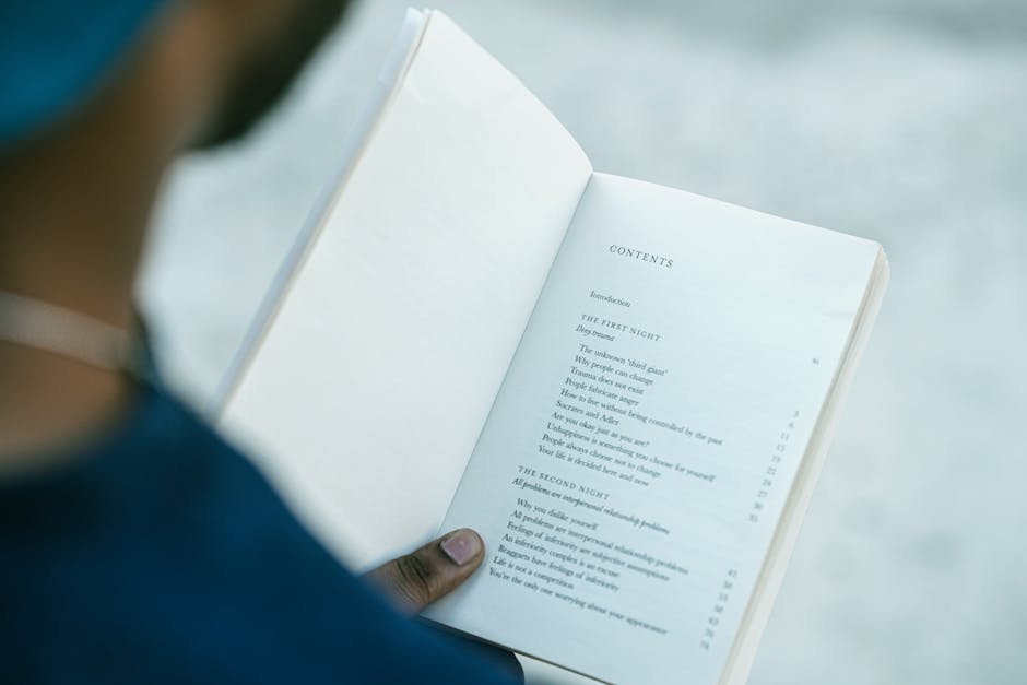 Close-up of hands holding an open book showing the table of contents.