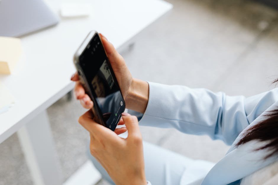 Close-up of a woman using a smartphone to take a photo in a modern office setting.