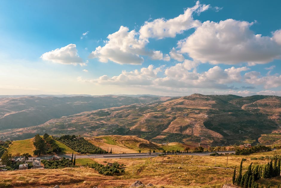 Breathtaking view of rolling hills under a blue sky with fluffy clouds in a rural countryside setting.